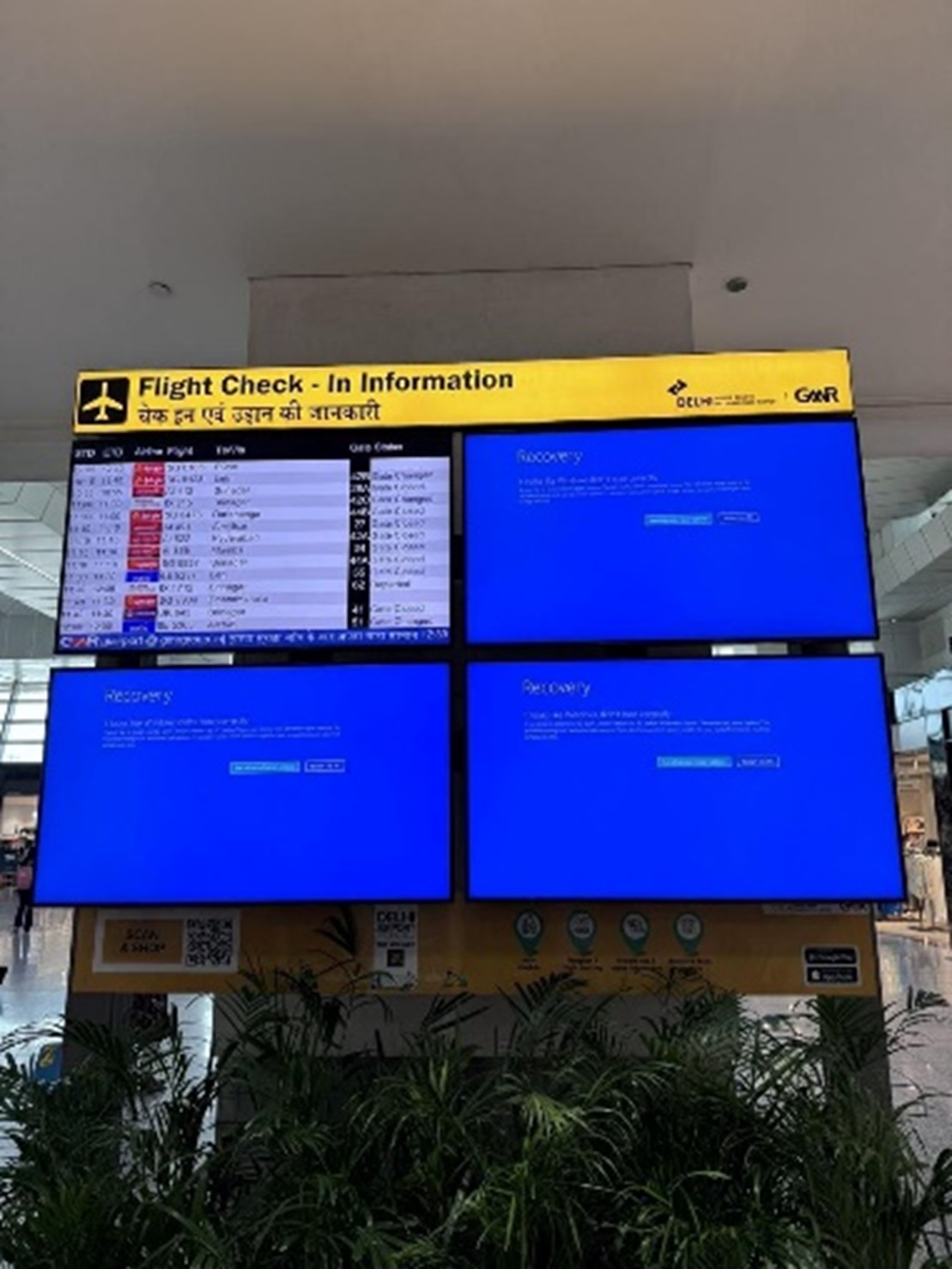 Flight information displays at Delhi International Airport showing system recovery messages.